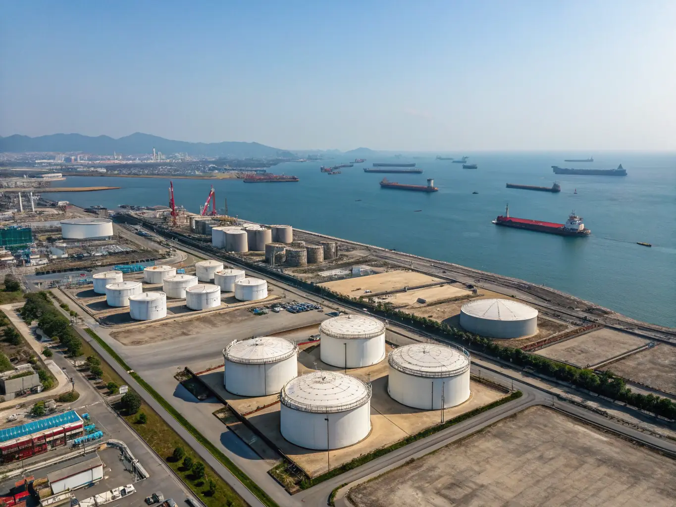 A high-resolution aerial photograph of the Singapore terminal, featuring modern oil storage tanks, maritime vessels docked at the port, and the Singapore Strait in the background, emphasizing advanced infrastructure and strategic Asia-Pacific access.